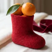Two clementines in a small red felt boot on ivory linen