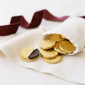 Chocolate coins in gold foil spilling from a linen pouch