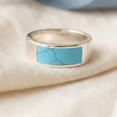 A wide silver band with a turquoise inlay, on ivory linen
