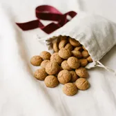 Small round pepernoten spilling from a linen bag
