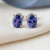 A pair of violet-blue tanzanite stud earrings, on ivory linen